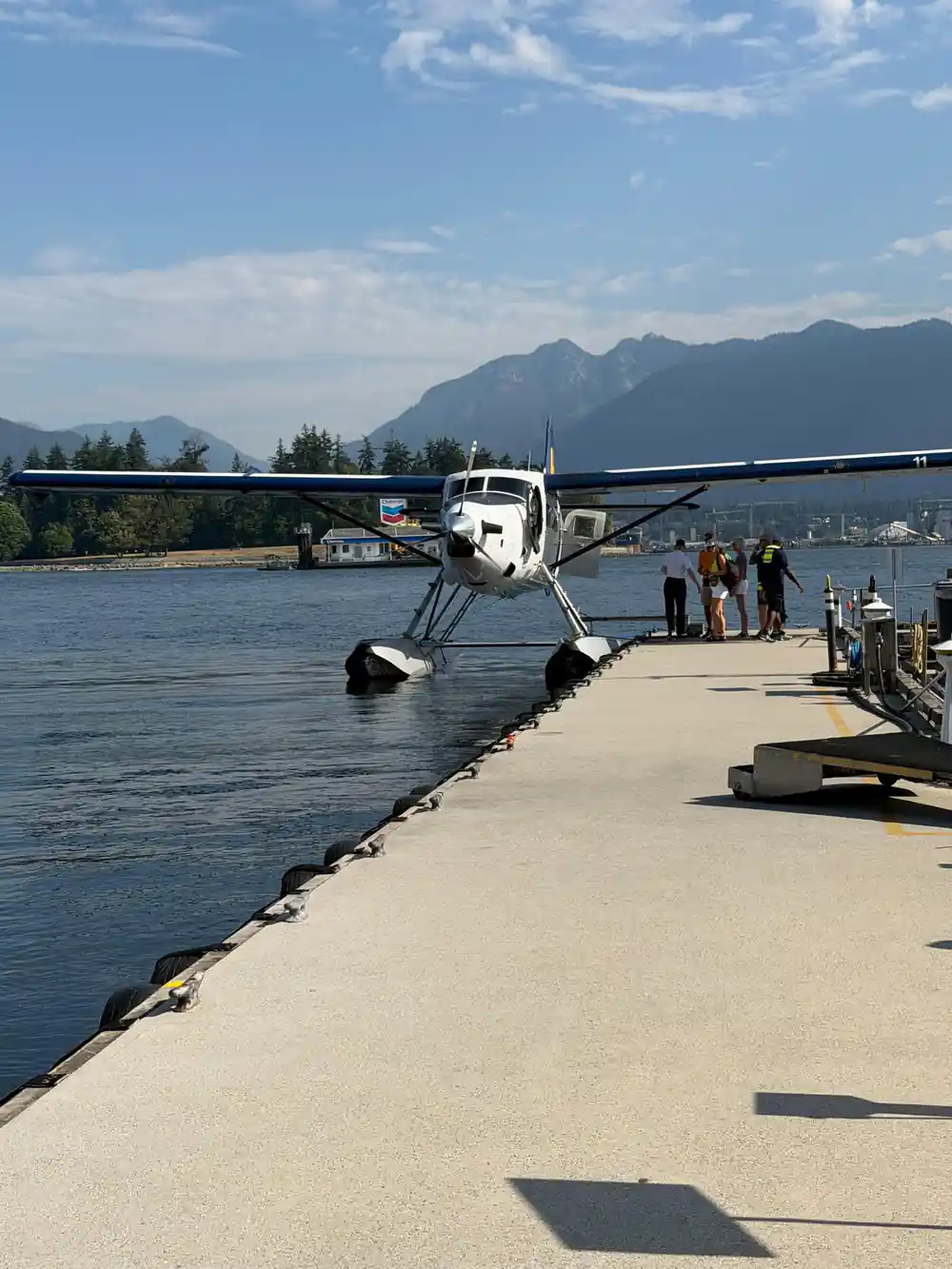 An aircraft at the end of a long dock with passengers walking out