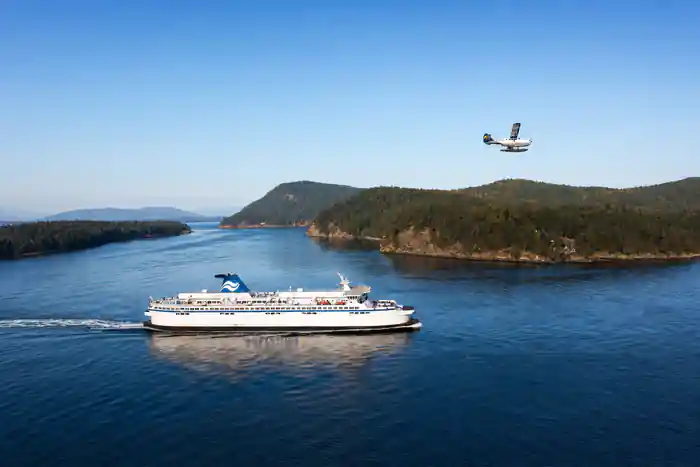 A BC Ferries ship below a seaplane passing overhead, both halves of the journey in one frame