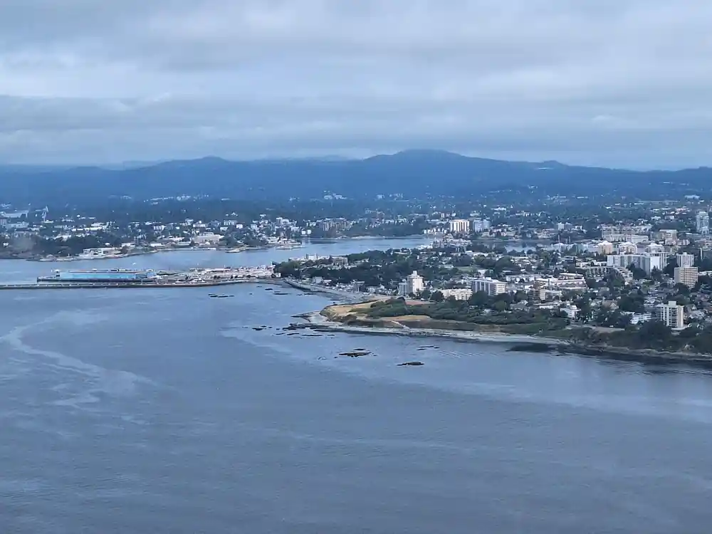 A city on a low headland with mountains behind, from the air