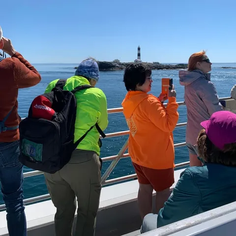 Passengers on deck as the ferry passes a lighthouse