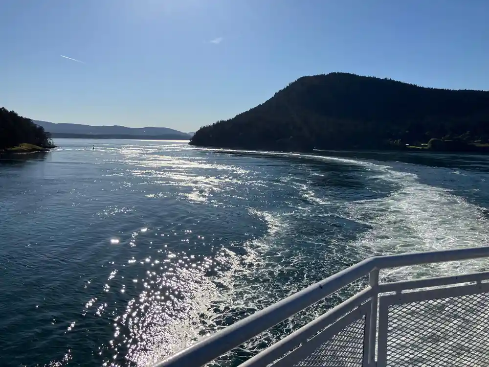 The ferry's wake spreading behind, a headland ahead