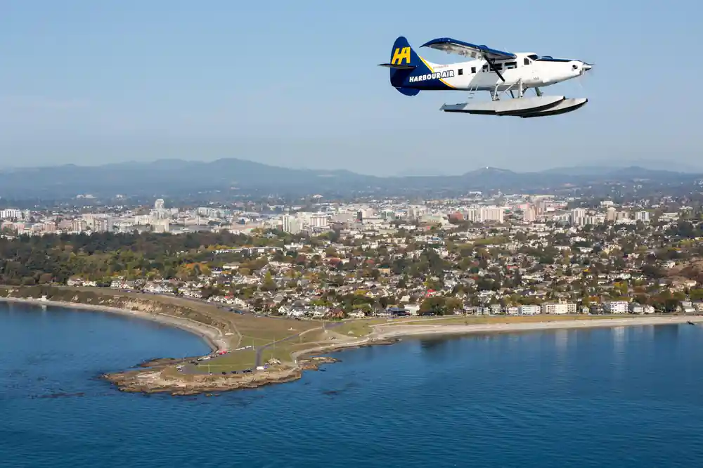 A Harbour Air aircraft banking above Victoria and its shoreline