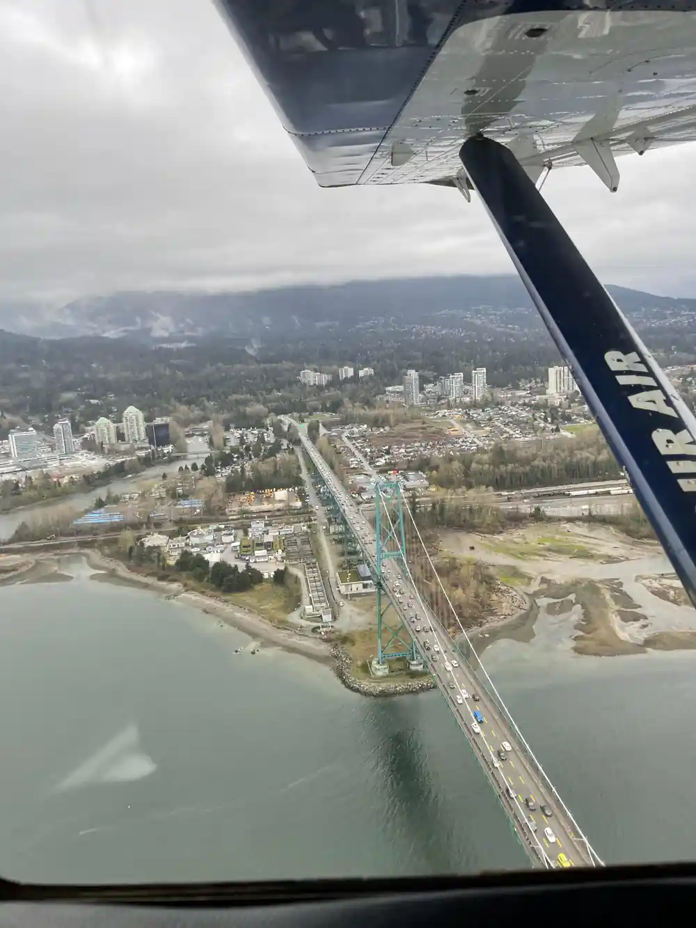 Lions Gate Bridge and the inlet from the air past the wing strut