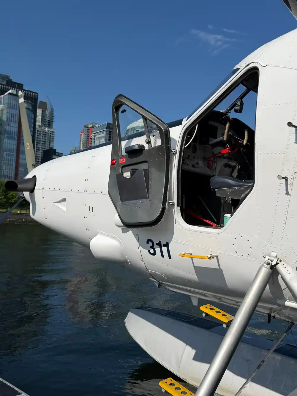 The open cabin door of a floatplane with the city behind