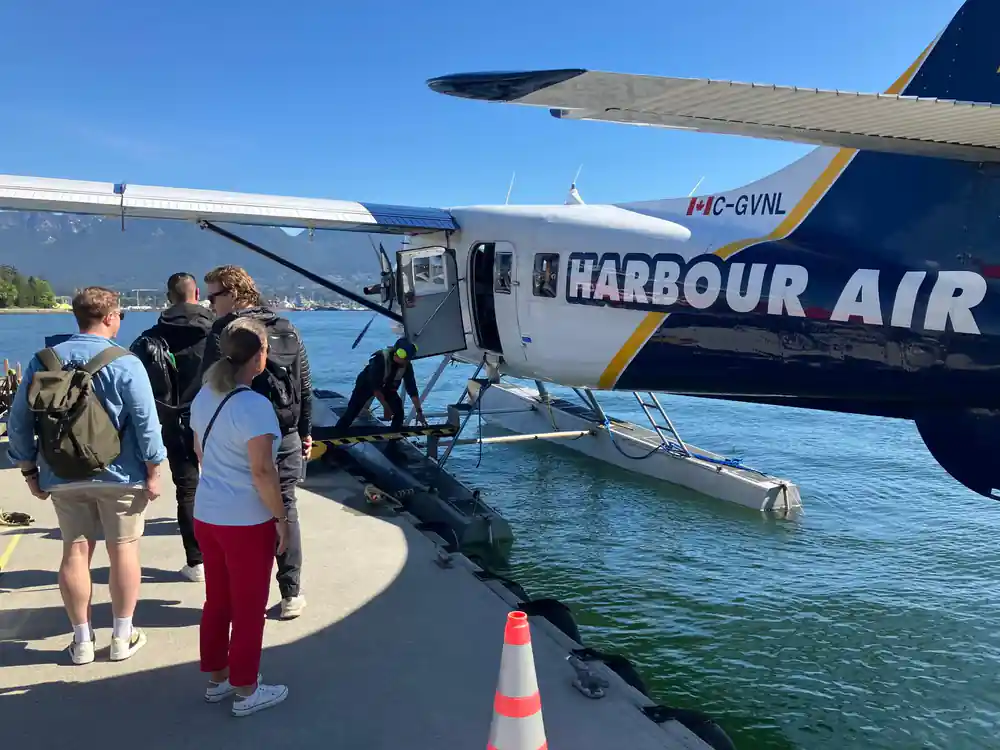 Passengers on the dock beside a Harbour Air aircraft on its floats