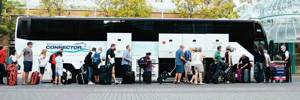 Passengers with wheeled cases loading at the side of a coach