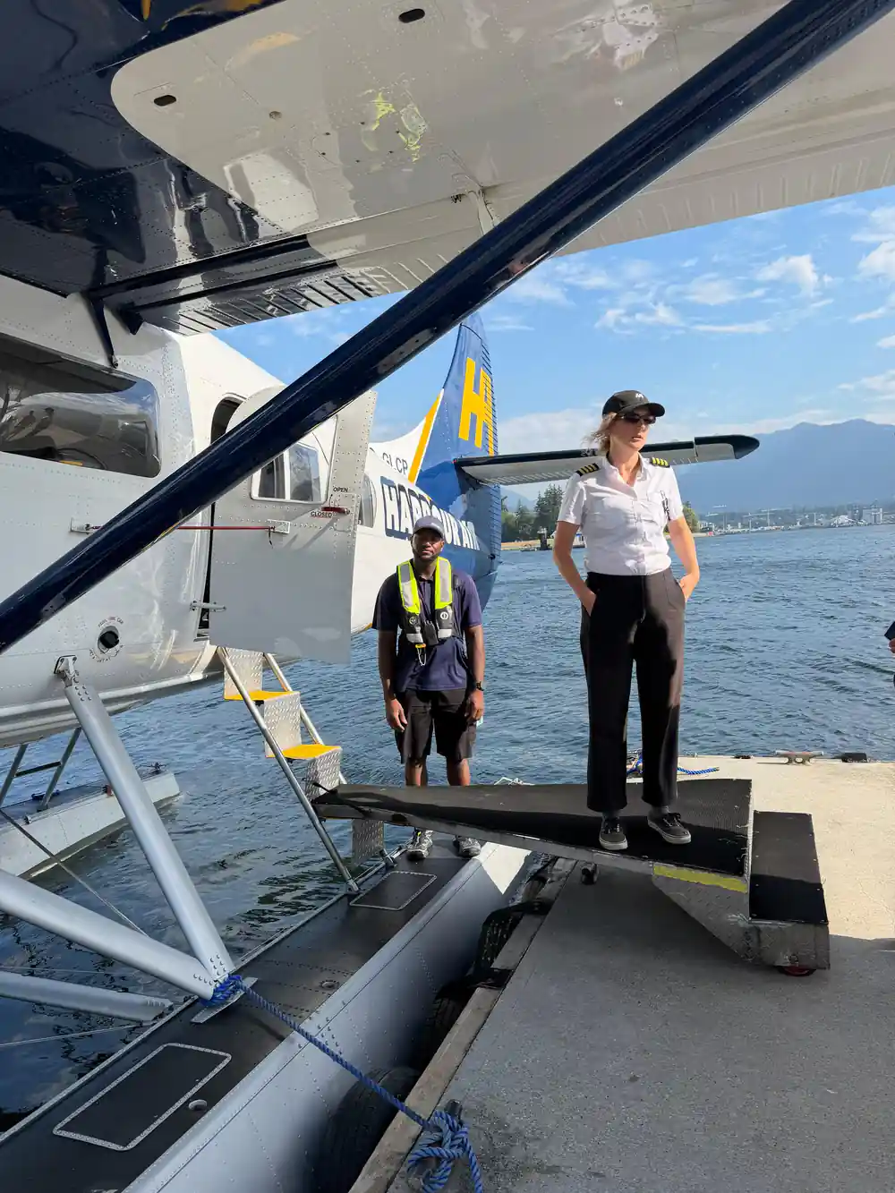 The pilot and a dockhand standing on the float beside the aircraft
