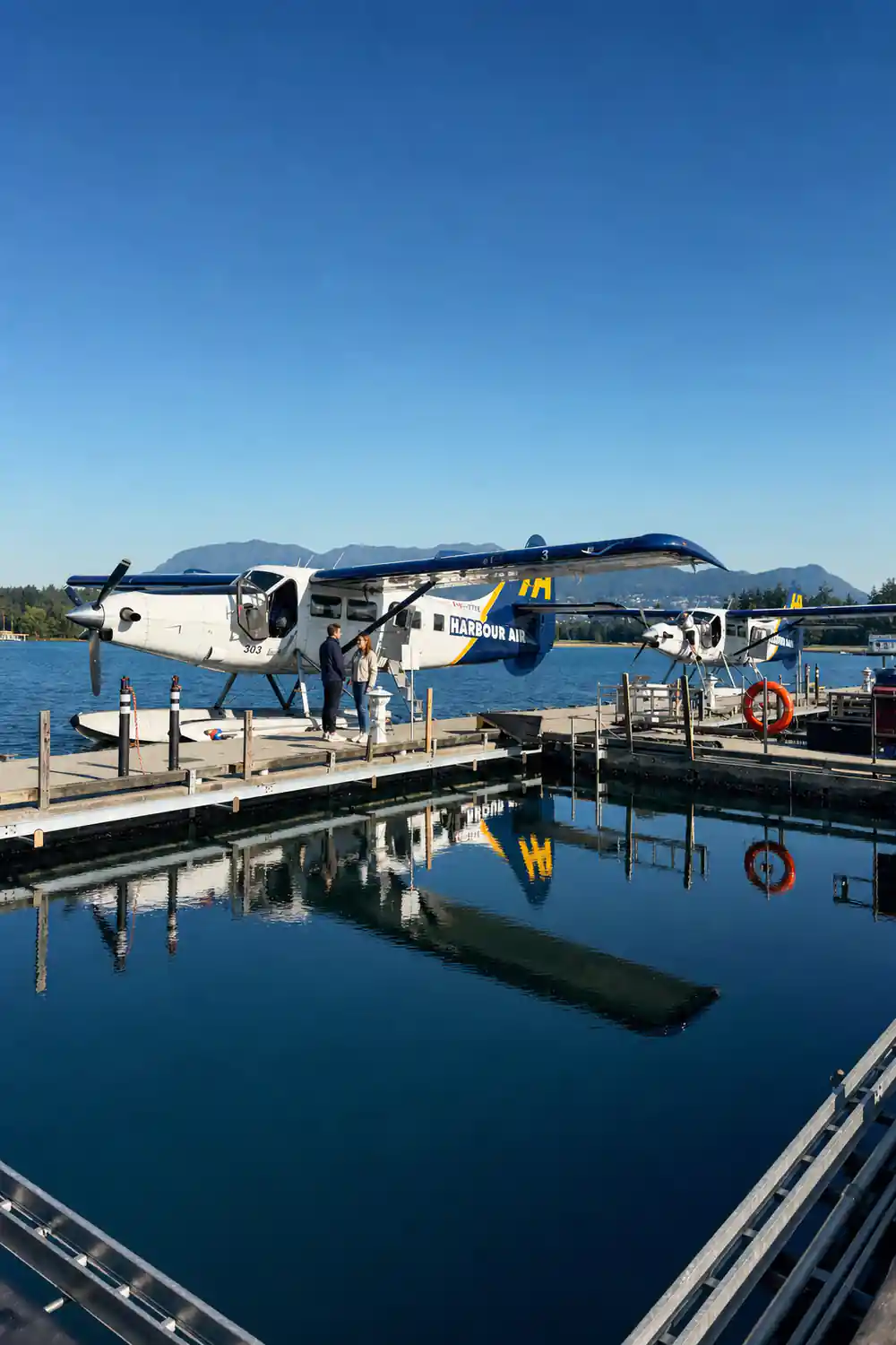 Two aircraft at the dock reflected in flat harbour water