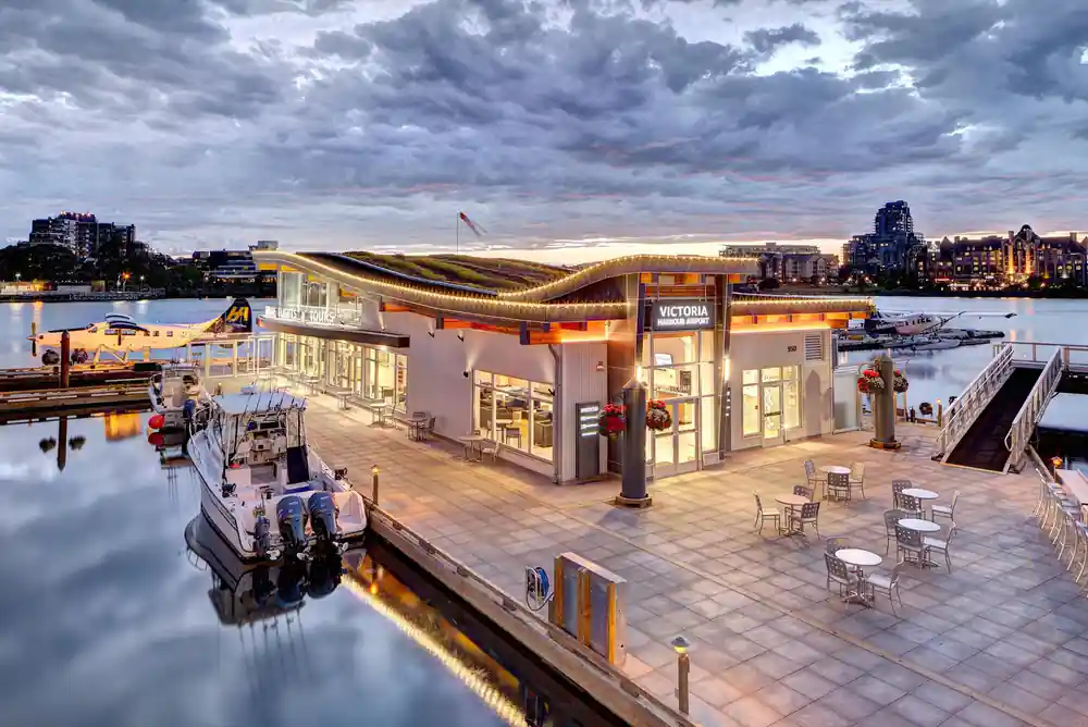 The Victoria harbour terminal building lit at dusk beside its dock