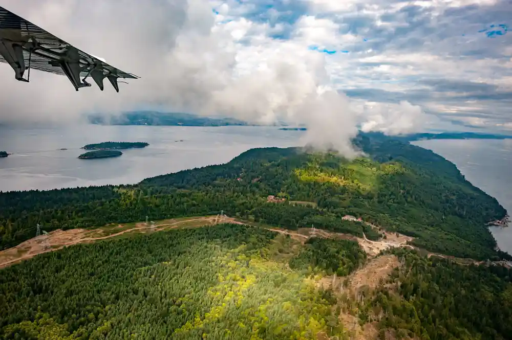 A wooded island seen from the air with cloud along its ridge